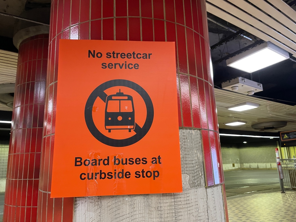 Arial sign: No streetcar service ¶ Board buses at curbside stop